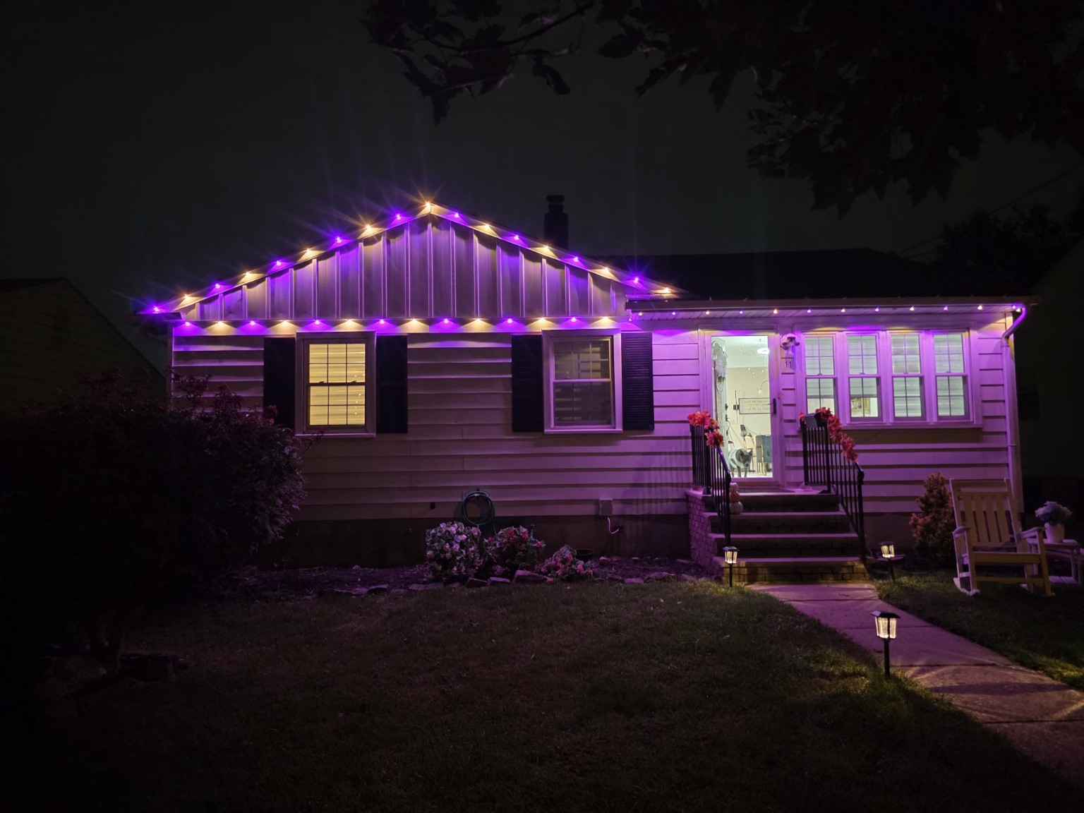 Carteret, New Jersey home with alternating purple and warm white permanent lights outlining the front gable and roof edge